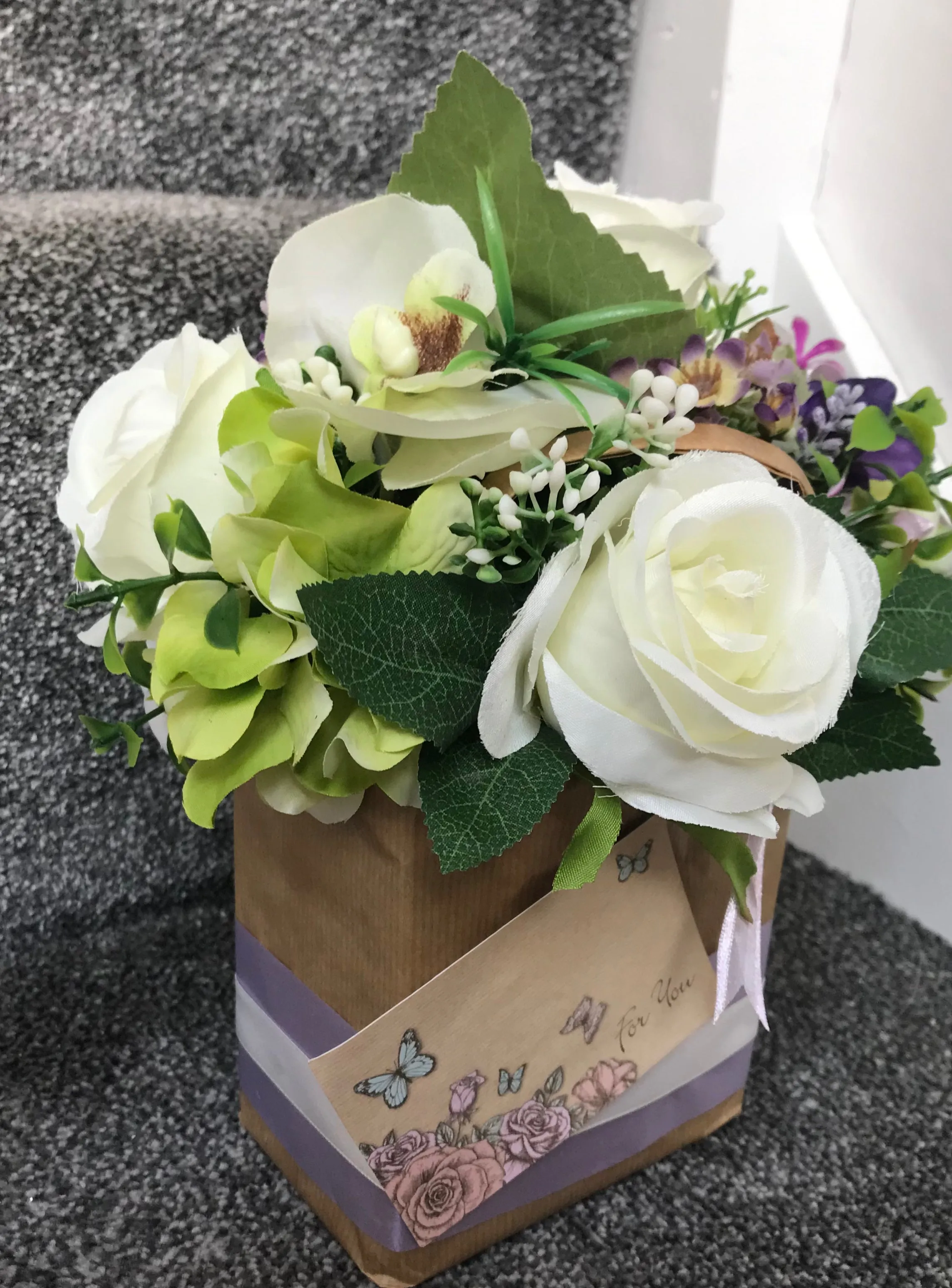 A flower arrangement of artificial roses in a gift bag